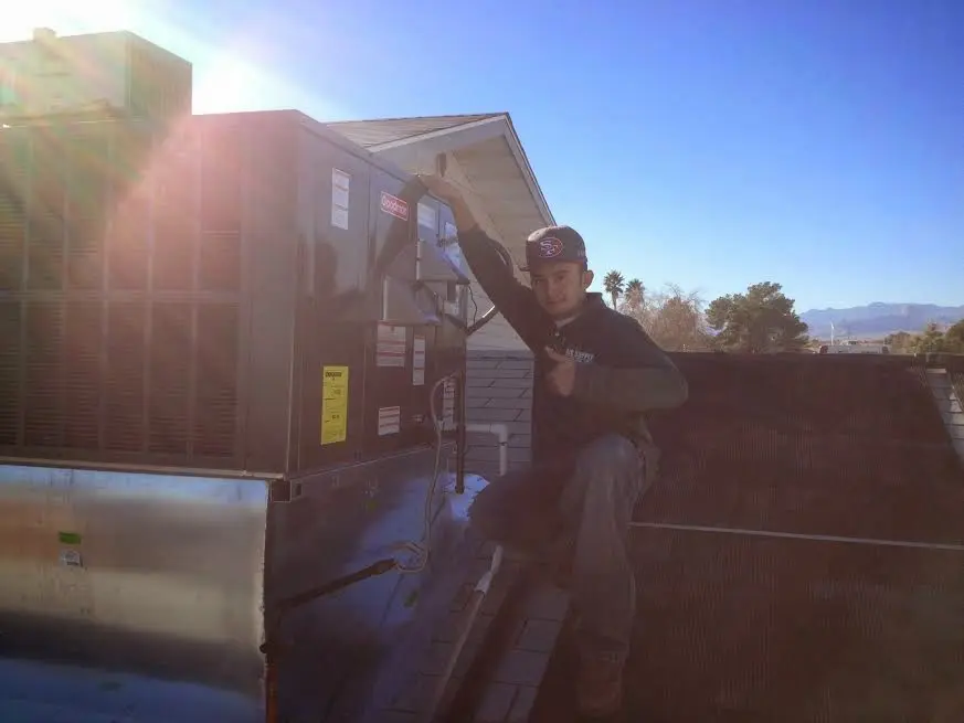 HVAC technician performing Air Duct Repair on a rooftop unit in Thatcher